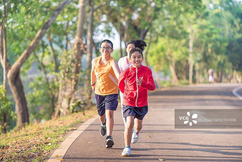 家庭运动快乐活跃的母亲和孩子在户外慢跑，在森林里跑步图片素材