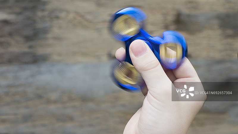 男孩玩着亮蓝色的指尖陀螺图片素材