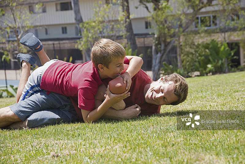 男孩在公园里与父亲玩橄榄球图片素材