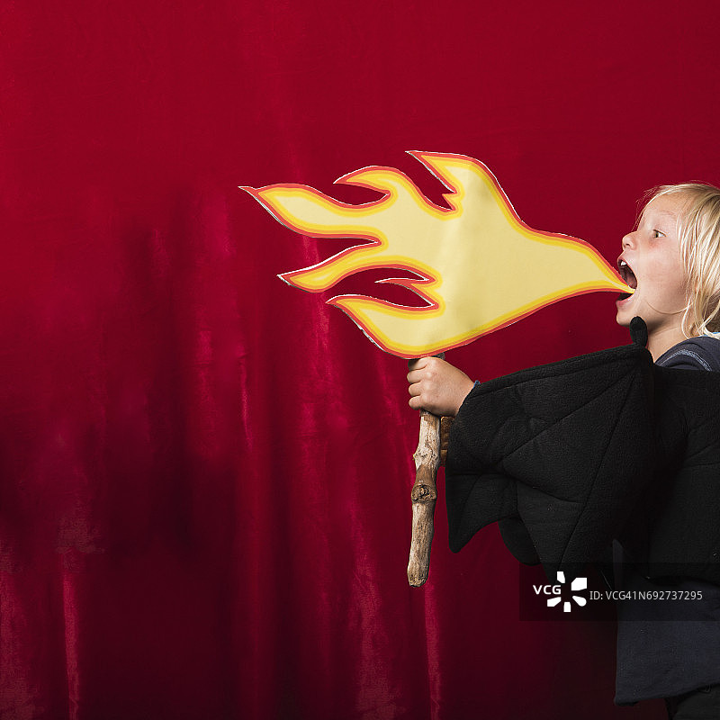 男孩拿着火焰纸板，假装喷火图片素材