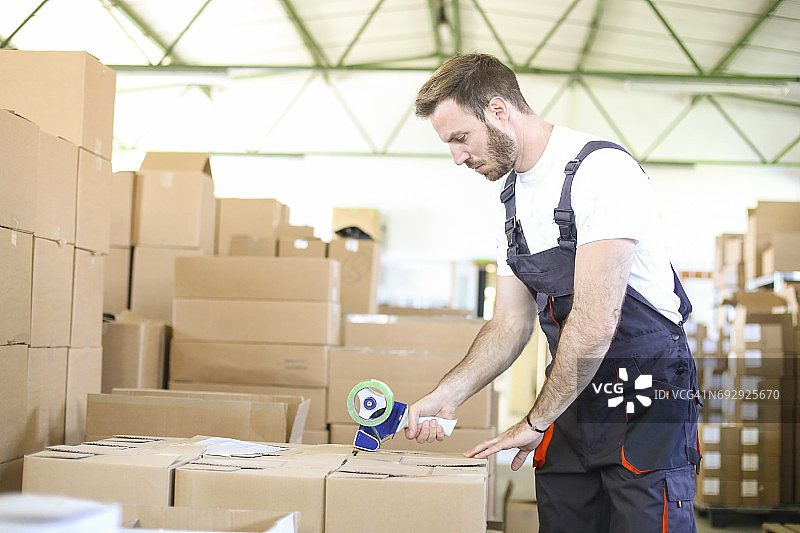 仓库工人使用胶带分配器图片素材