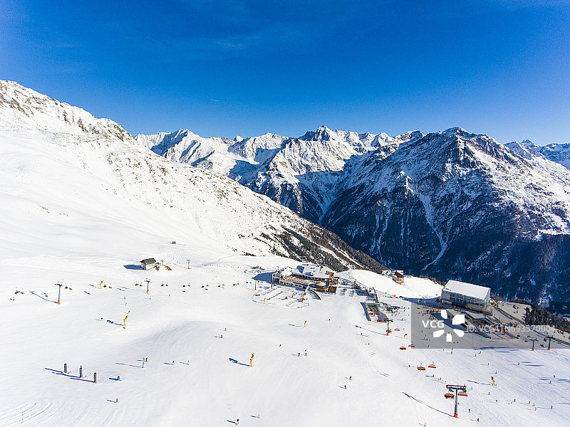 阿尔卑斯山滑雪胜地，滑雪缆车和人们在斜坡上滑雪的全景航拍图片素材