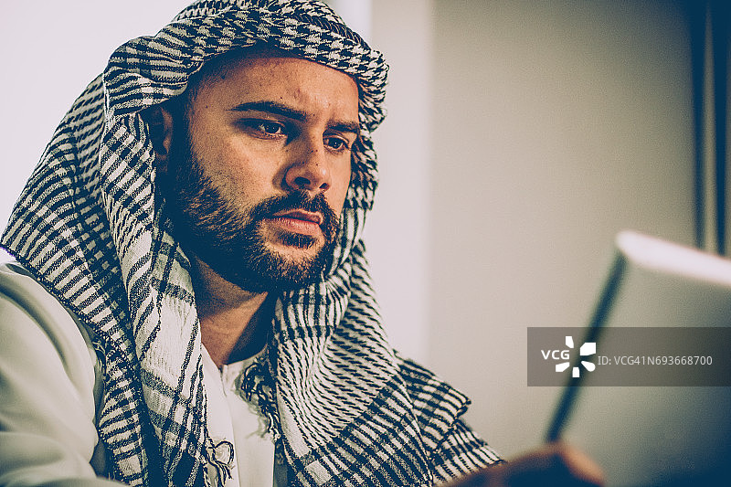 在办公室看笔记本电脑的年轻阿拉伯男子图片素材