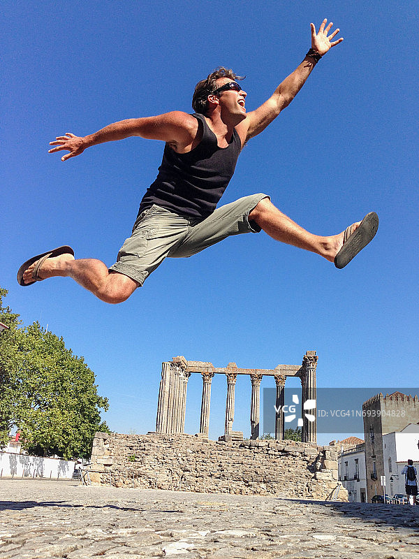 男人在埃武拉古罗马神庙（也称为狄安娜神庙）前跳跃图片素材