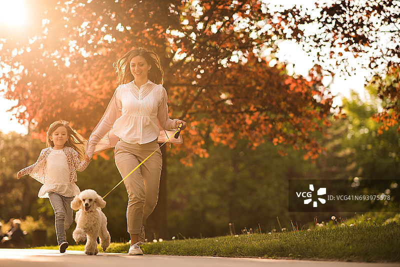在公园里和狗狗一起奔跑的快乐母女图片素材