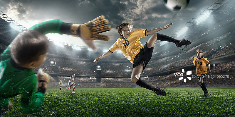 足球儿童球员进球。守门员试图击球图片素材