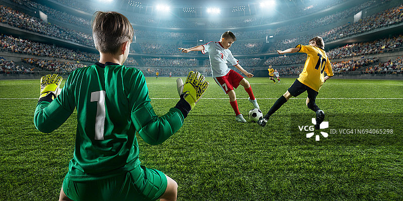 足球儿童球员进球。守门员试图击球图片素材