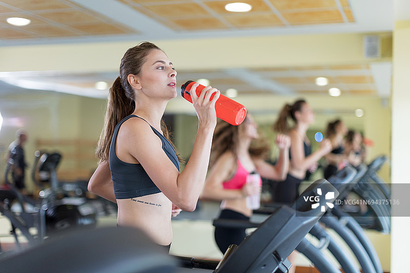 在跑步机上喝水的女子图片素材