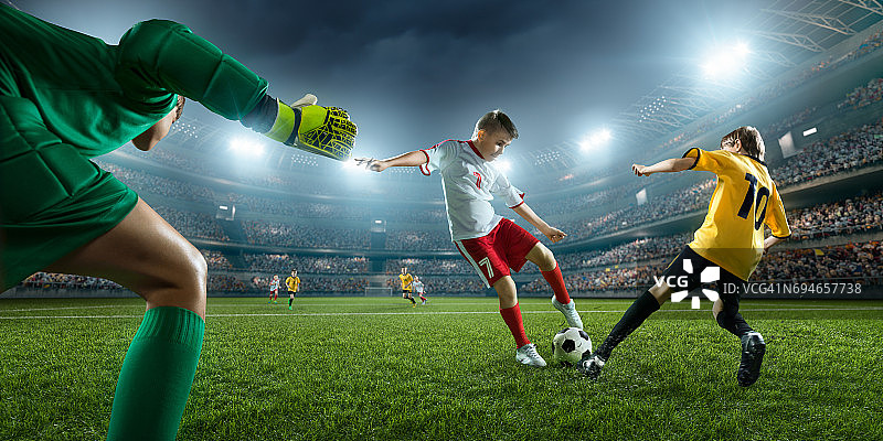 足球儿童球员进球。守门员试图击球图片素材