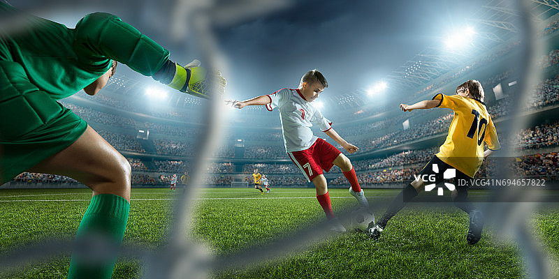 足球儿童球员进球。守门员试图击球图片素材