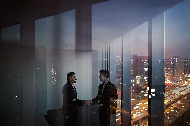 商人在夜晚的办公室里握手图片素材