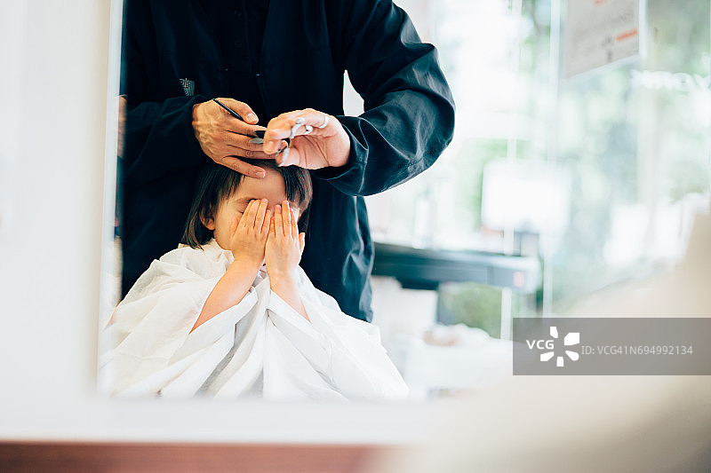 小女孩在理发时遮住脸图片素材