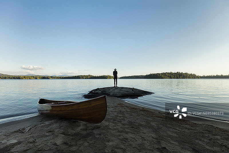 男子站在岩石上眺望湖面图片素材