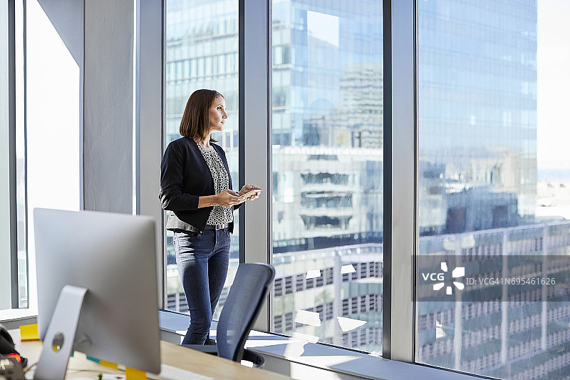在办公室里望向窗外的女性高管图片素材