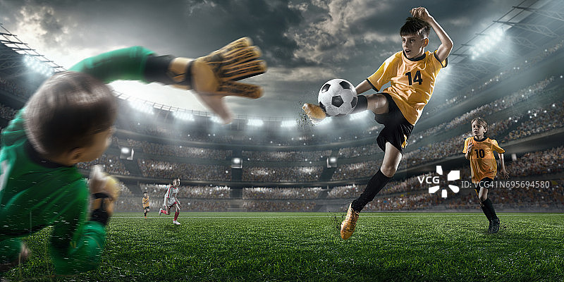 足球儿童球员进球。守门员试图击球图片素材