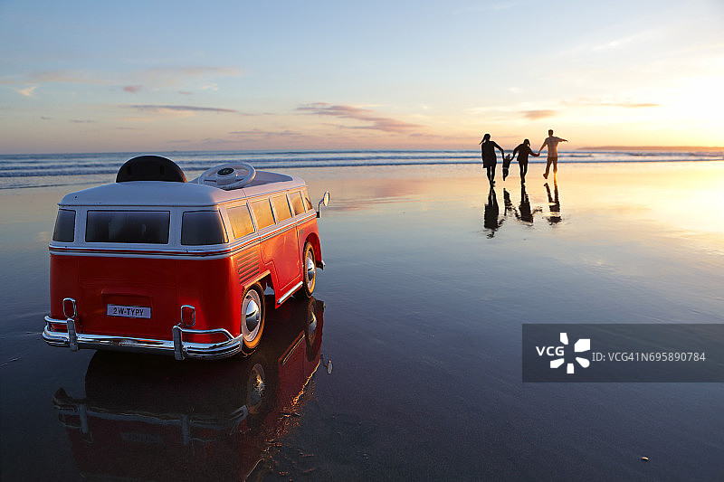 日落时在沙滩上玩玩具车的家庭图片素材