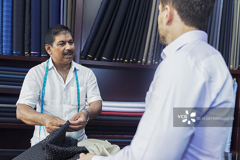 裁缝为商人定制西装，讨论各种面料选择图片素材