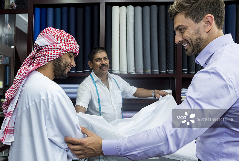 商人帮助他的阿拉伯朋友决定新西装的面料图片素材