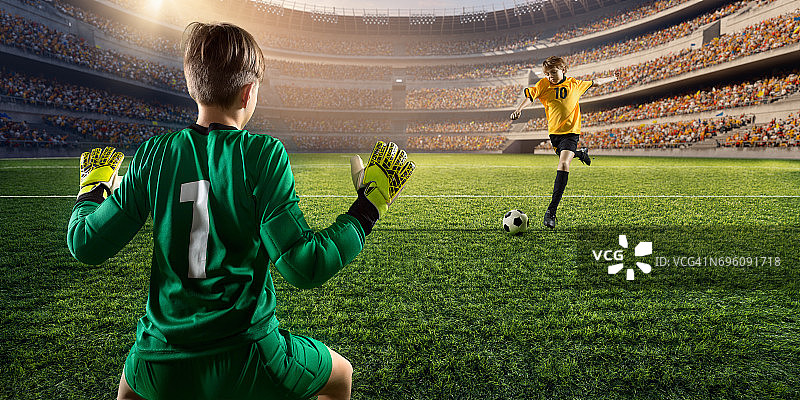 足球儿童球员进球。守门员试图击球图片素材