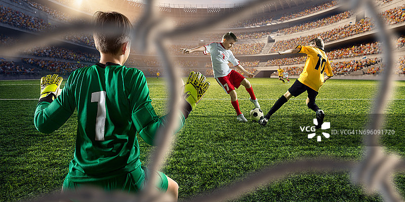 足球儿童球员进球。守门员试图击球图片素材