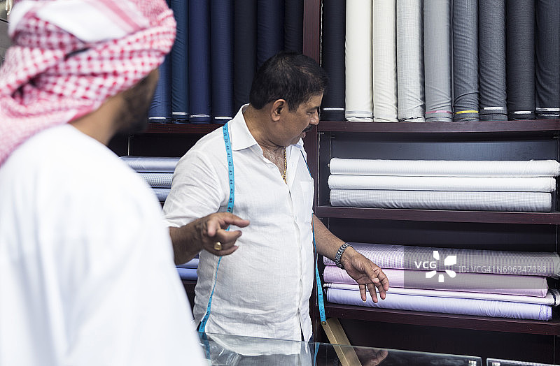 裁缝向阿拉伯顾客展示高档面料样品图片素材