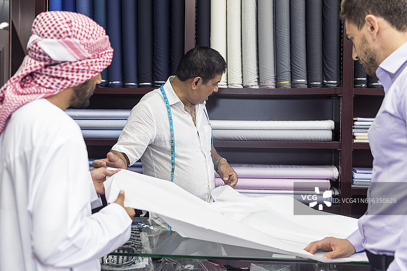 商人帮助其中东朋友选择定制西装的面料图片素材