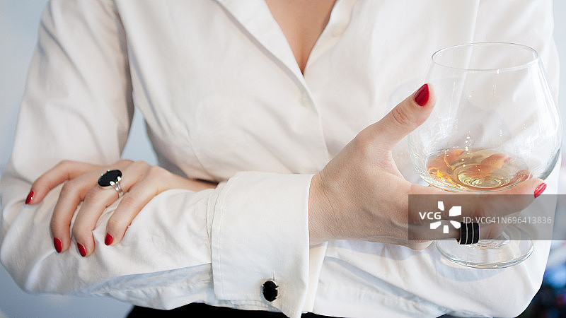 拿着干邑酒杯、涂着红色指甲油的女人图片素材