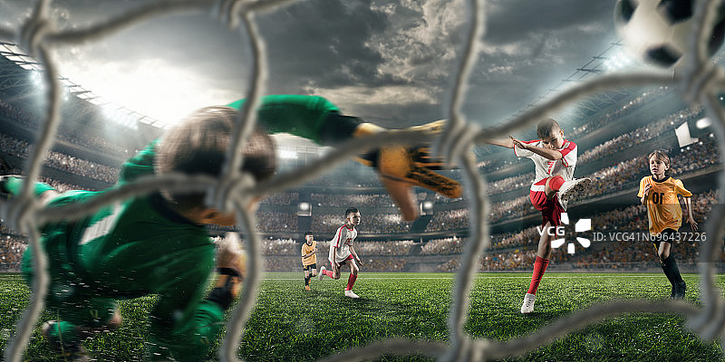 足球儿童球员进球。守门员试图击球图片素材