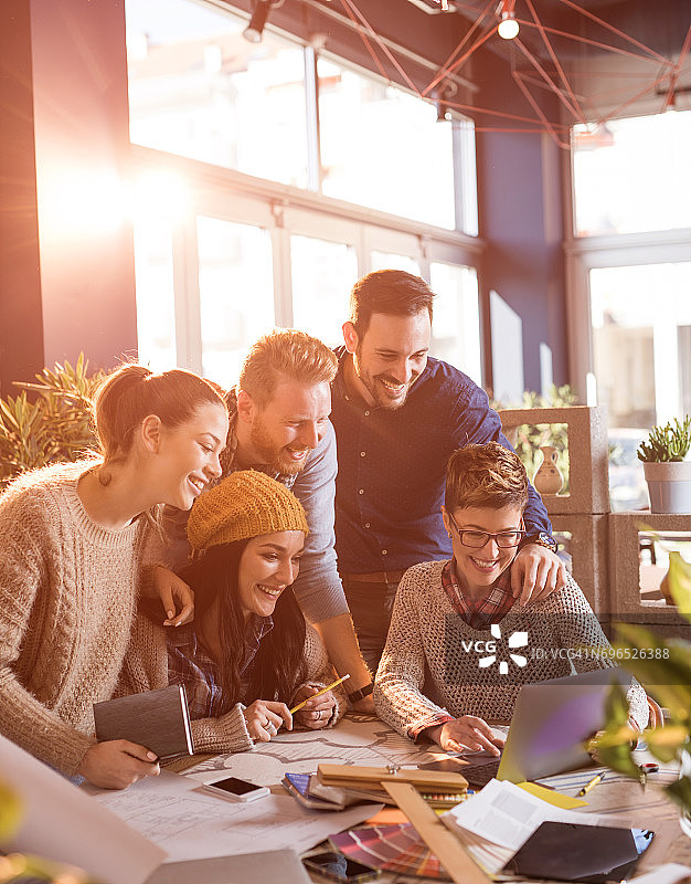 在休闲办公室使用笔记本电脑的快乐创业团队图片素材