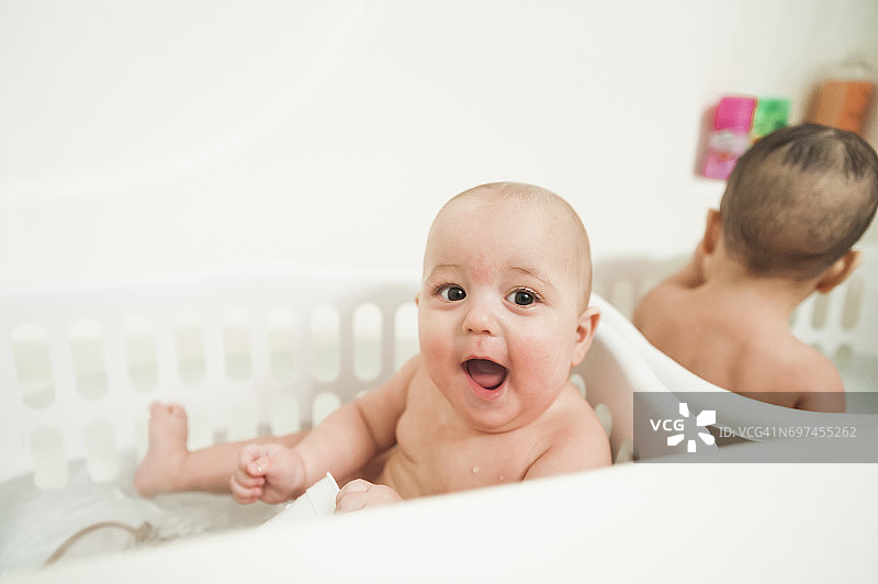 在浴缸里一起玩的10个月大的双胞胎男孩图片素材