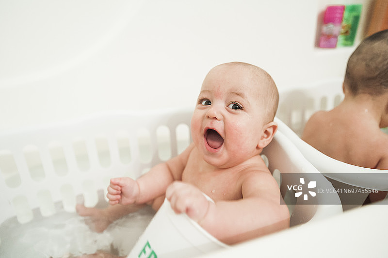 在浴缸里一起玩的10个月大的双胞胎男孩图片素材