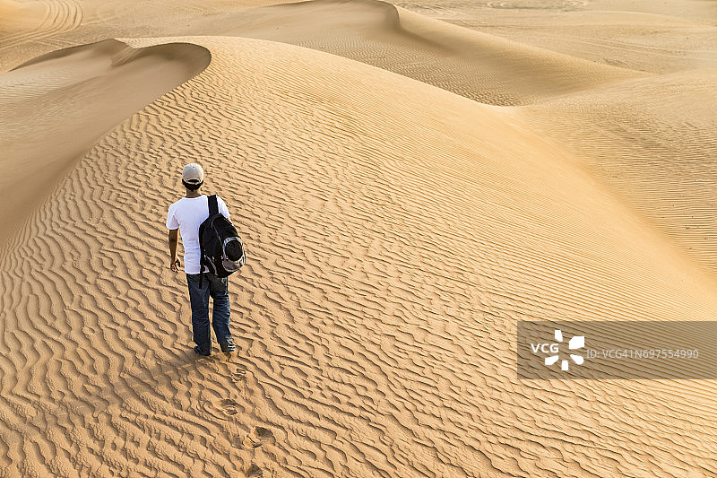 青少年背着背包探索阿拉伯的沙丘图片素材