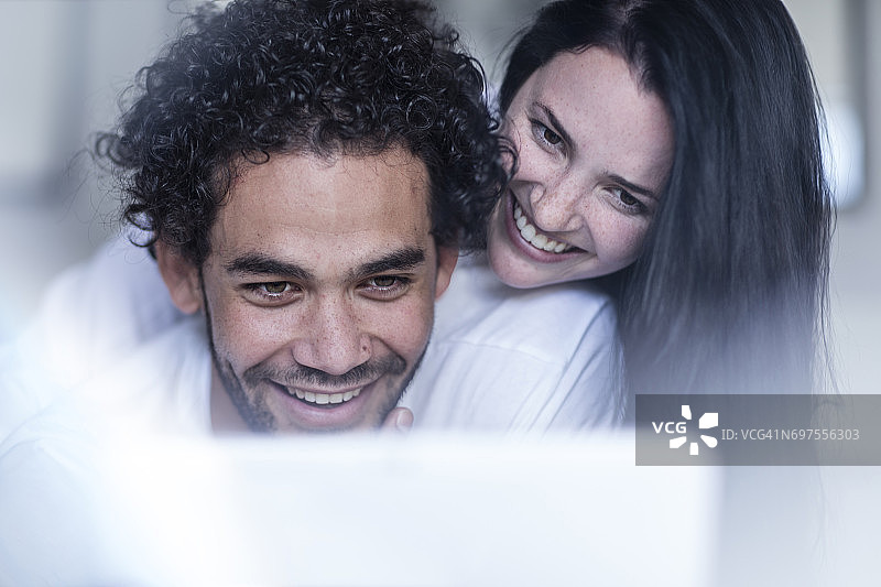 微笑的年轻情侣看着平板电脑图片素材