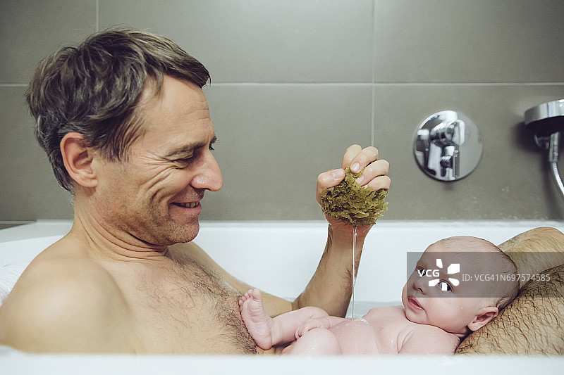 父亲和宝宝用天然海绵洗澡图片素材
