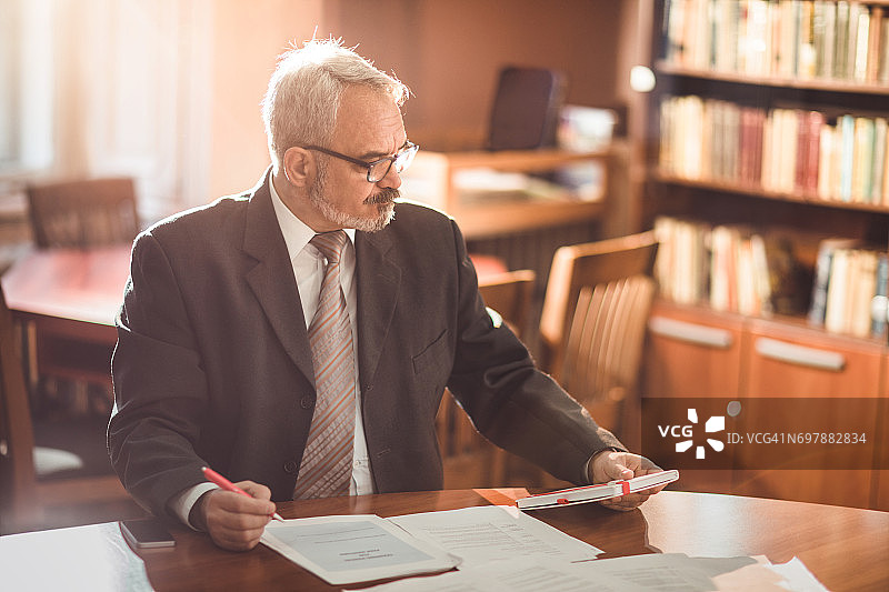 在办公室阅读报告的年长商人图片素材