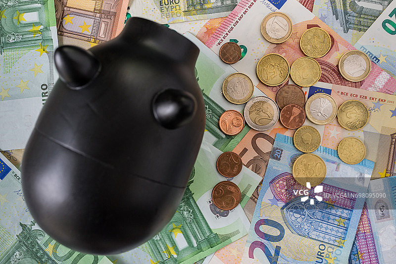 欧元硬币和纸币，带黑色小猪储蓄罐，金融储蓄概念图片素材