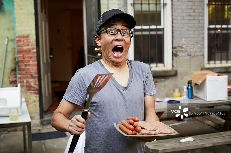 惊讶的日本男人在后院拿着一盘生肉图片素材