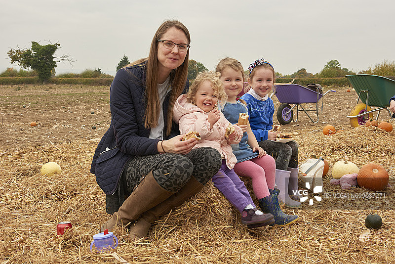 中年妇女和三个女孩在南瓜地里野餐图片素材
