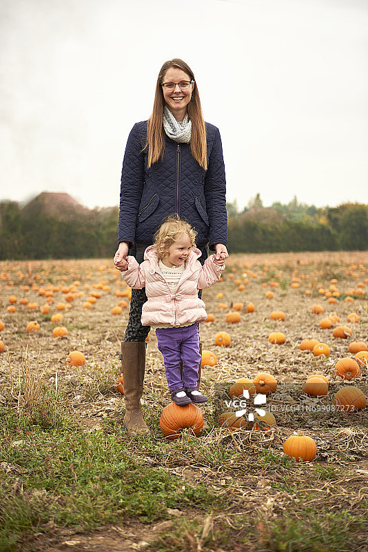 中年女子与幼儿女儿站在田野南瓜上的肖像图片素材