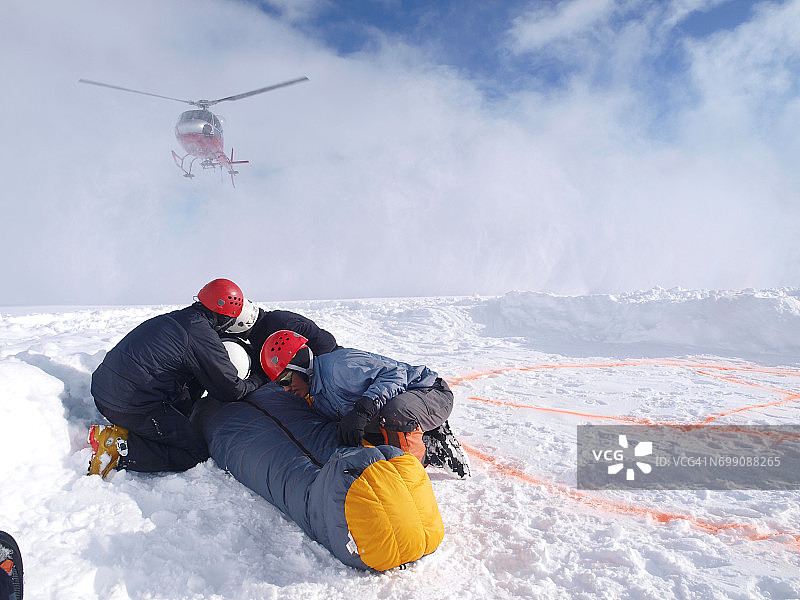 在德纳里山(原名德纳里山)，登山救援人员正在保护一名受害者，以躲避降落直升机的顺风。图片素材