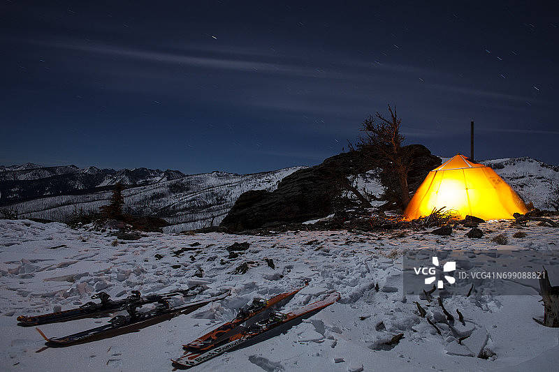 滑雪板和苦根山脉中发光的帐篷，星轨划过天空图片素材