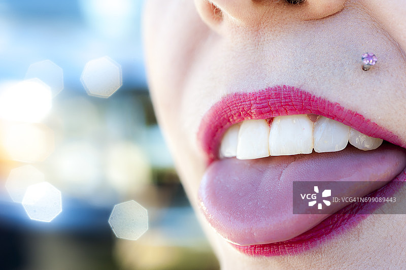 露出舌头、牙齿和穿孔的女人嘴部特写图片素材