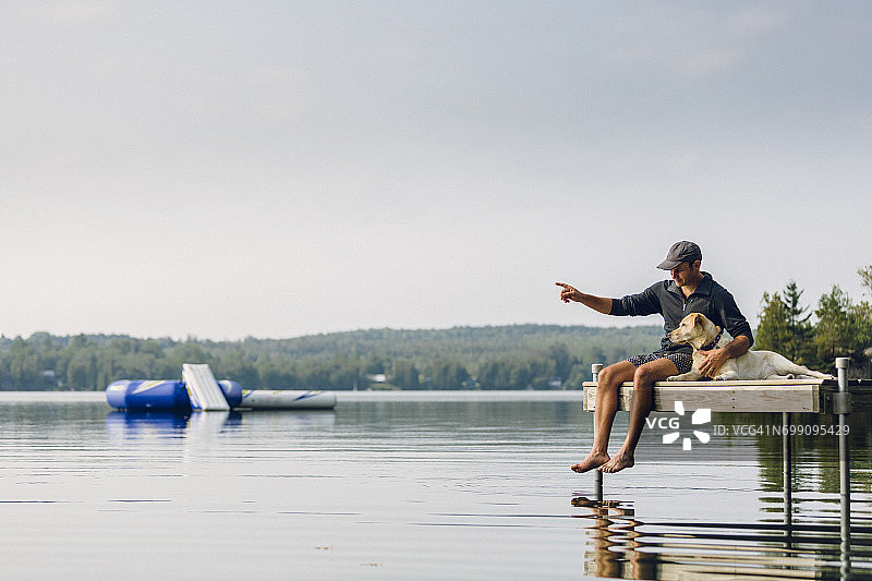 男人和小狗坐在湖边的码头上图片素材
