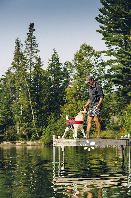 男人和小狗坐在湖边的码头上图片素材