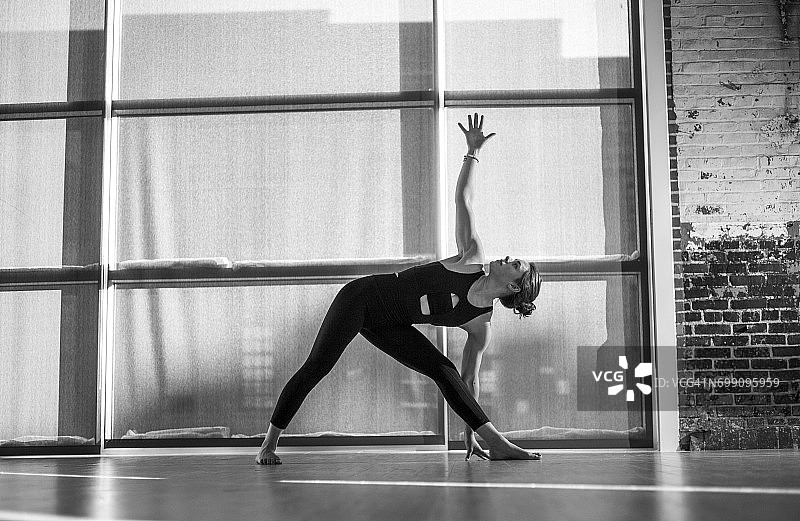 瑜伽馆中做三角式瑜伽的女瑜伽教练图片素材