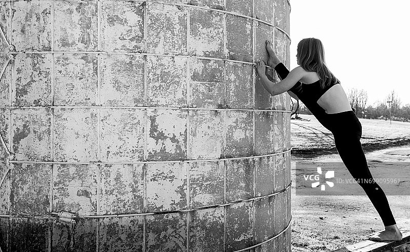 柔韧的女子在筒仓旁伸展瑜伽服图片素材