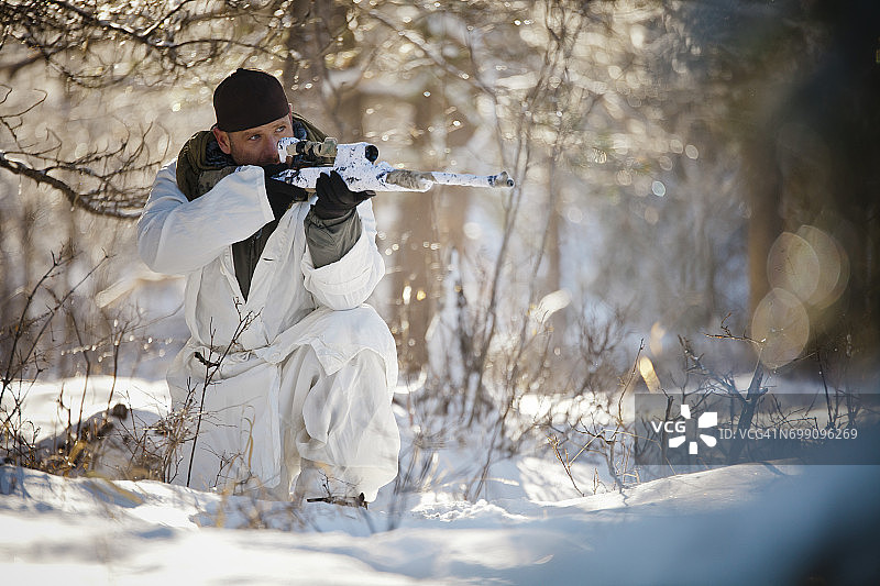 猎人穿着冬季迷彩服在雪林中瞄准图片素材