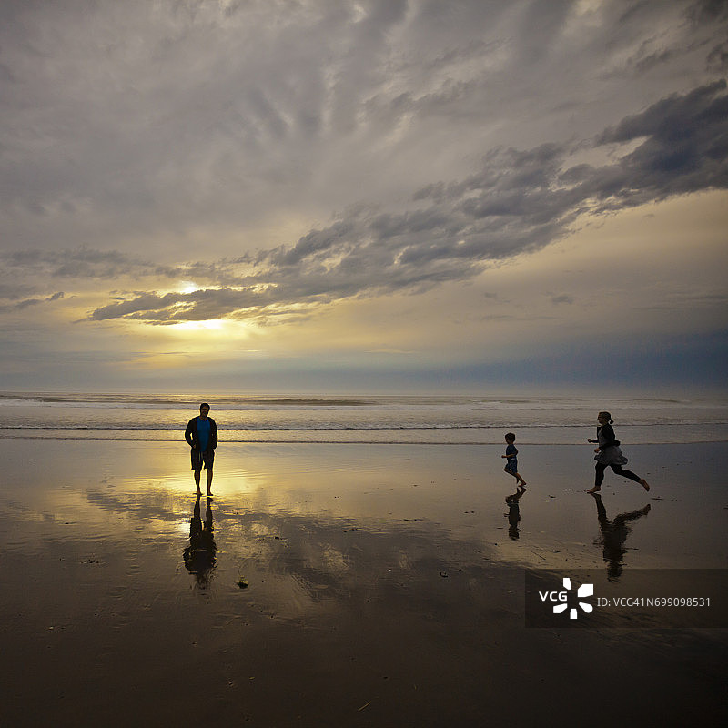 在俄勒冈州罗克away海滩享受生活的一家三口的剪影图片素材