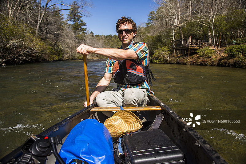 男人在佐治亚州北部平静的查塔胡奇河上划独木舟图片素材