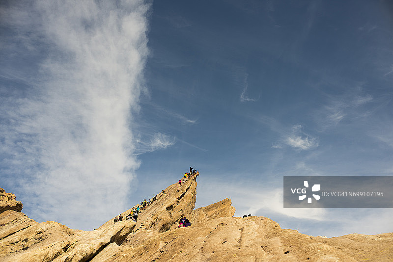 人们在加利福尼亚沙漠中攀登锯齿状岩层图片素材